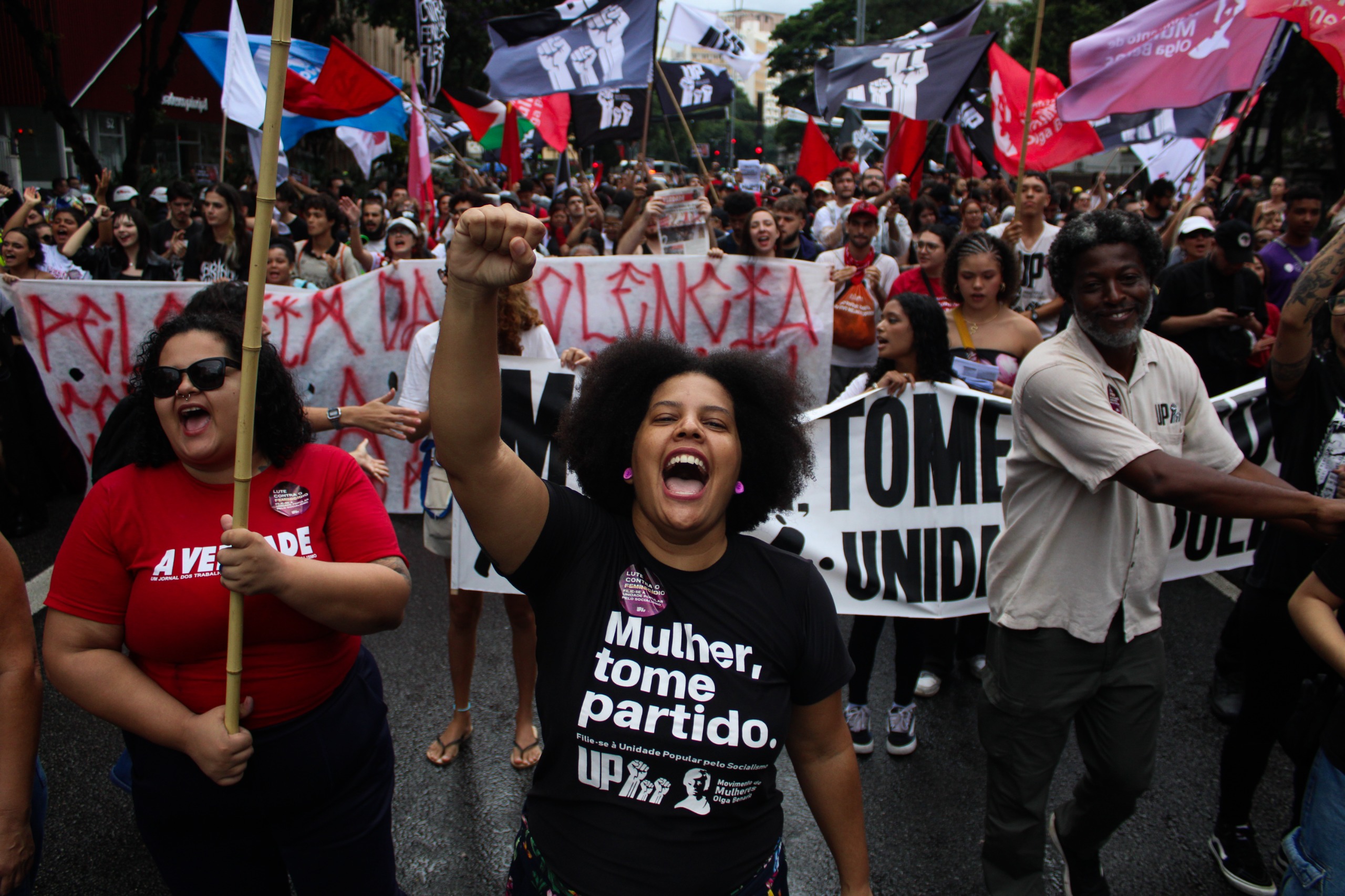 Samara Martins com punho em riste, à frente de manifestação na rua.